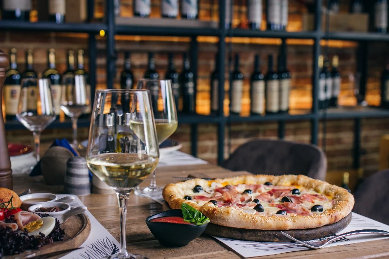 Pizza with prosciutto and olives with wine
